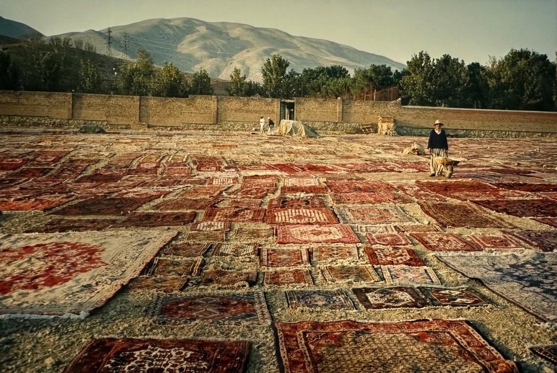 Hundreds of Persian rugs laid out to dry against Iranian mountains